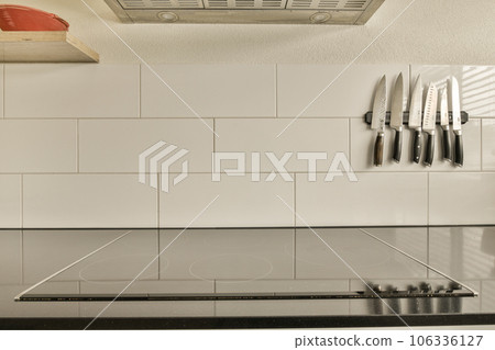a kitchen with white tiles on the wall and black counters in the center of the photo is blurry 106336127