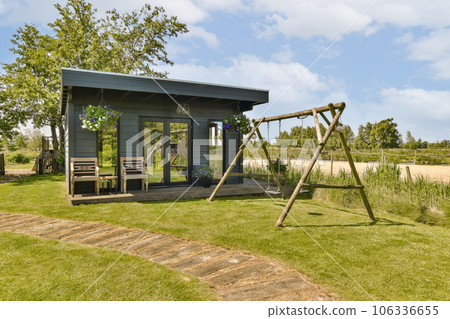 an outdoor play area with swings and swings in the grass, surrounded by blue sky and white fluffy clouds 106336655