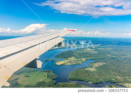 View of airplane wing, blue skies and green land during landing. Airplane window view. 106337753