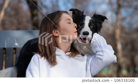 Caucasian woman hugging her dog Border Collie while sitting on a bench in autumn park. Caucasian woman hugging her dog Border Collie while sitting on a bench in autumn park. 106338100