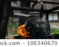 Heating a kettle over a bonfire while camping 106340670