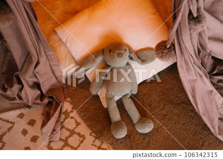 Cute toy rabbit lying in bed indoors 106342315