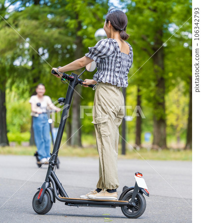 A young and cute woman running refreshingly with an electric kickboard in the refreshing sunlight and greenery | Electric kickboard image A young and cute woman running refreshingly with an electric kickboard in the refreshing sunlight and greenery | Electric kickboard image 106342793