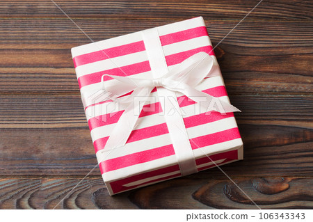 wrapped Christmas or other holiday handmade gift box in color paper with ribbon on colored background. Present box, decoration of gift on colored table, top view with copy space wrapped Christmas or other holiday handmade gift box in color paper with ribbon on colored background. Present box, decoration of gift on colored table, top view with copy space 106343343