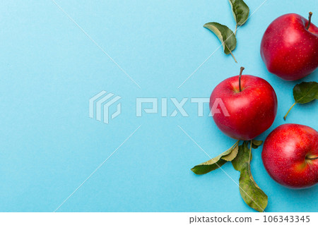 Many red apples on colored background, top view. Autumn pattern with fresh apple above view with copy space for design or text Many red apples on colored background, top view. Autumn pattern with fresh apple above view with copy space for design or text 106343345