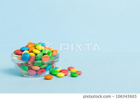 Multicolored candies in a bowl on a colored background. birthday and holiday concept. Top view with copy space 106343683