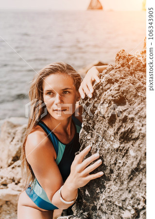 Woman travel summer sea. A happy tourist in a blue bikini enjoying the scenic view of the sea and volcanic mountains while taking pictures to capture the memories of her travel adventure. Woman travel summer sea. A happy tourist in a blue bikini enjoying the scenic view of the sea and volcanic mountains while taking pictures to capture the memories of her travel adventure. 106343905