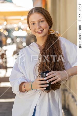 Teen child girl enjoying drinking morning coffee hot drink, relaxing, taking a break in city street 106344224