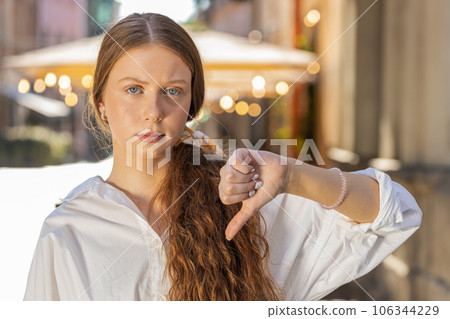Upset child girl woman showing thumbs down sign, disapproval, dissatisfied bad work, mistake in city Upset child girl woman showing thumbs down sign, disapproval, dissatisfied bad work, mistake in city 106344229