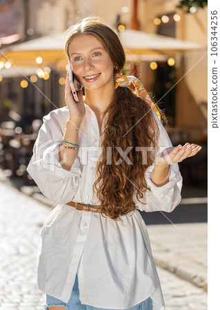 Happy child girl having remote conversation talking on smartphone, good news gossip in city street 106344256