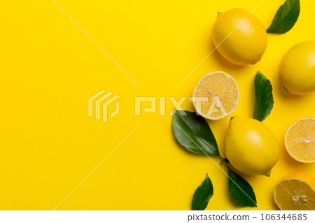 Many fresh ripe lemons with green leaves on colored background, top view, space for text Many fresh ripe lemons with green leaves on colored background, top view, space for text 106344685