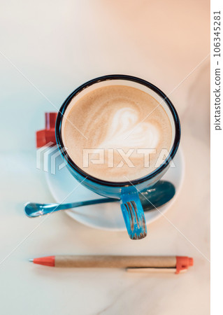 View from above. Coffee with milk in a blue cup on a wooden table in a cafe View from above. Coffee with milk in a blue cup on a wooden table in a cafe 106345281