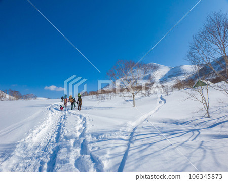 People walking on a snowy field with snowboards on their backs (Hokkaido, Niseko Annupuri North Slope Side) 106345873