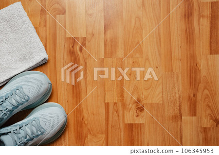 New light blue green female running shoes and towel on emty wooden floor. Stylish monochrome shoes for active people that incorporate new health technology. Top view 106345953