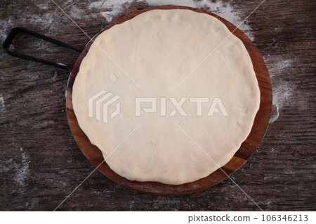 Fresh raw dough for pizza or bread baking on wooden cutting board on dark rustic background. Top view 106346213