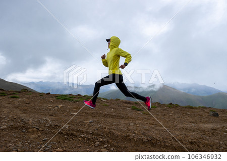 Woman trail runner cross country running at high altitude mountain peak 106346932