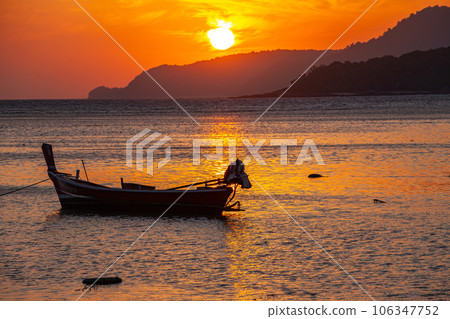 amazing yellow sky of sunrise above the island.  The brilliant yellow hue of the sky created a breathtaking scene as the sun slowly rose over the island. fishing boats parking on the golden sea. 106347752