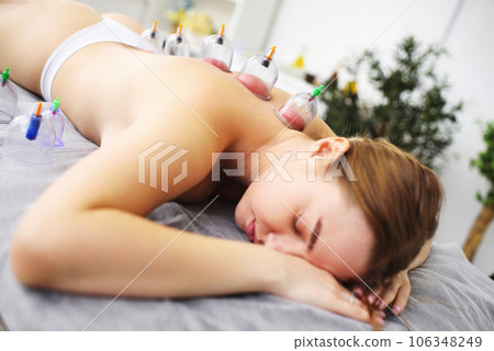 Hijama - method of vacuum bloodletting. The specialist makes cupping therapy for the patient. 106348249