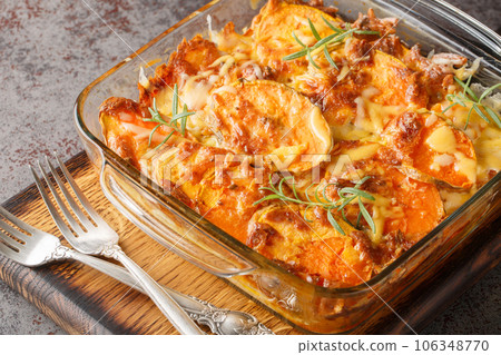 Homemade sweet potato gratin with cheddar cheese, eggs and rosemary close-up in a glass form. Horizontal 106348770