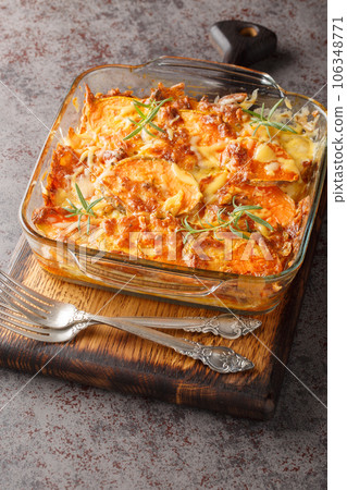 Vegetarian sweet potato gratin with cheddar cheese and rosemary close-up in a glass form. Vertical Vegetarian sweet potato gratin with cheddar cheese and rosemary close-up in a glass form. Vertical 106348771