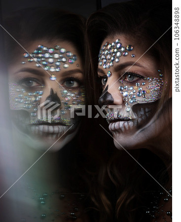 young woman with rhinestone makeup for Dia de los Muertos young woman with rhinestone makeup for Dia de los Muertos 106348898