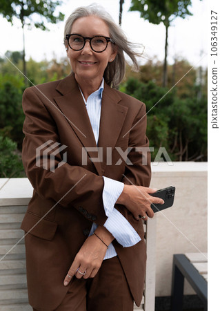 a gray-haired middle-aged woman dressed in a stylish suit is waiting for a business meeting on the 106349127