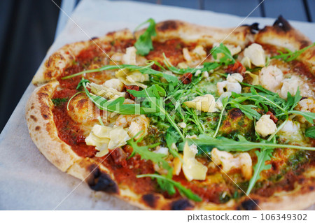Delicious pizza on thin dough on the table. Delicious pizza on thin dough on the table. 106349302