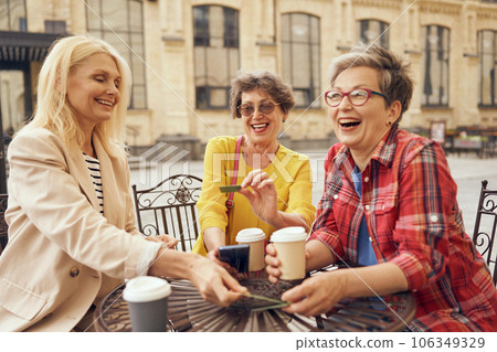 Mature women sitting in cafe, drinking coffee and laughing while enjoying spending time together 106349329