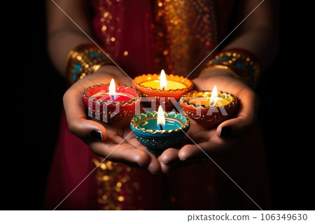 Woman hands with henna holding colorful clay diya lamps lit during diwali celebration 106349630