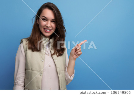smiling woman pointing finger at empty space on blue background smiling woman pointing finger at empty space on blue background 106349805