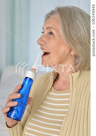 Portrait of a old woman cleaning teeth with an irrigator 106349948