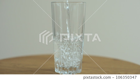 Water pouring to glass. Cold drink pours into a glass. Water in high glass cup. 106350347
