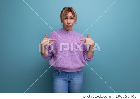 portrait of a perplexed sad blonde young woman in a lavender sweater on a bright plain background portrait of a perplexed sad blonde young woman in a lavender sweater on a bright plain background 106350403
