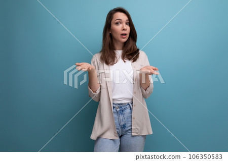 confused young dark-haired lady in informal clothes on a blue background confused young dark-haired lady in informal clothes on a blue background 106350583