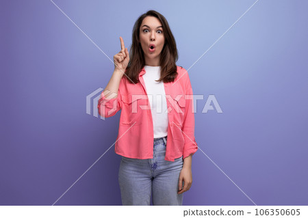 a young woman in a pink shirt and jeans got an insight and points a finger up on a studio isolated a young woman in a pink shirt and jeans got an insight and points a finger up on a studio isolated 106350605