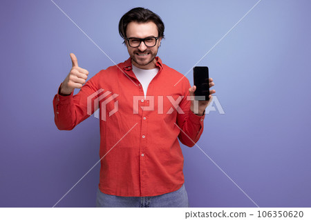 smart confident young brunette man in glasses advertises smartphone 106350620