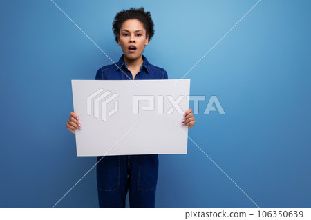 young pretty hispanic business woman with fluffy hair dressed in blue denim suit holding billboard young pretty hispanic business woman with fluffy hair dressed in blue denim suit holding billboard 106350639