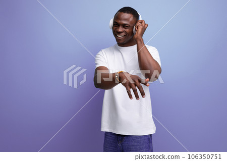 energetic joyful dark-skinned young american guy in a white t-shirt listens to a podcast in energetic joyful dark-skinned young american guy in a white t-shirt listens to a podcast in 106350751