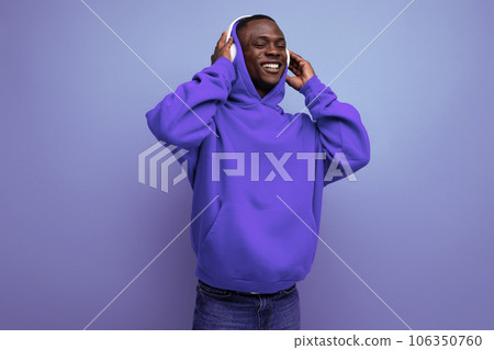 cool energetic dark-skinned american man with modern wireless headphones on the background with copy 106350760