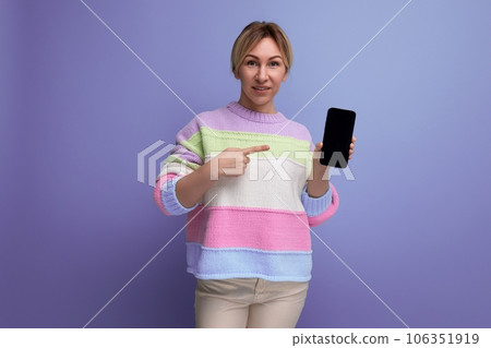 attractive blond young woman showing phone screen with mockup on purple background with copy space 106351919