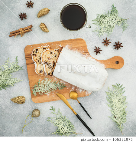 Christmas composition with stollen cake on a wooden board, cutlery and coffee cup on gray table Christmas composition with stollen cake on a wooden board, cutlery and coffee cup on gray table 106351975