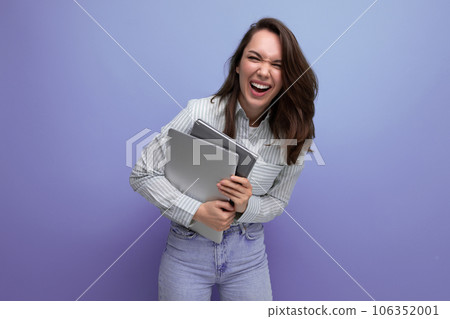 successful 20s brunette lady in shirt and jeans holding work laptop and papers 106352001