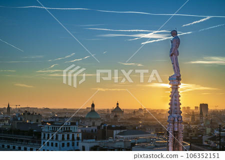 Sunset over city of Milan. Shades of orange, pink, and purple spread across the sky Sunset over city of Milan. Shades of orange, pink, and purple spread across the sky 106352151
