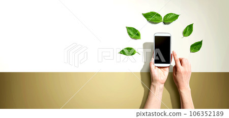 Person holding smartphone with green leaves Person holding smartphone with green leaves 106352189
