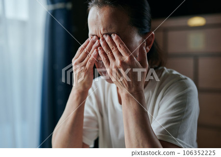 Senior woman holding her eyes with both hands Senior woman holding her eyes with both hands 106352225