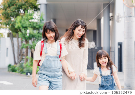 Two girls going to school holding hands with their mother 106352479