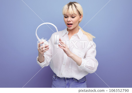 young positive caucasian woman with a short haircut dressed in a white shirt and jeans uses wireless 106352790