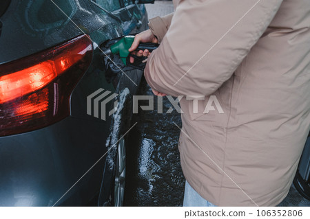 a man fills up his car at a gas station 106352806