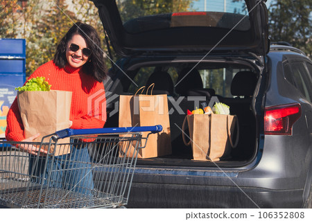 woman put packages in car trunk 106352808