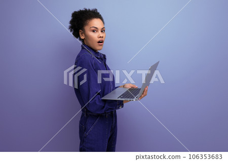 young successful woman with dark skin and black curly hair dressed in a blue denim suit works 106353683